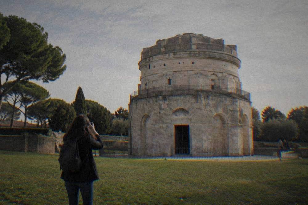 A visitor photographing the mausoleum from the lawn with the full round profile in frame