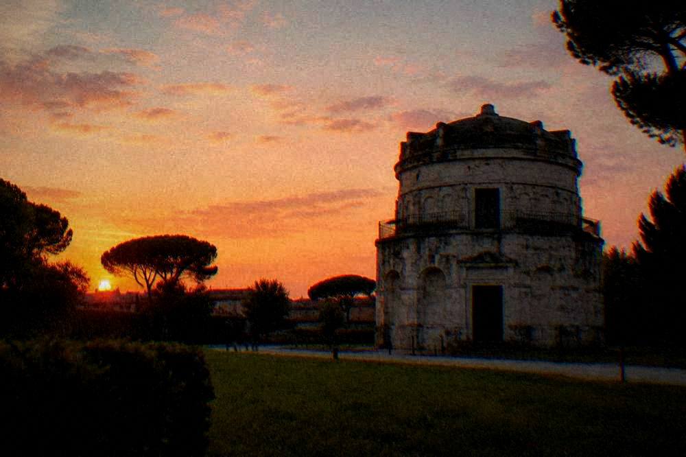 The round mausoleum silhouetted against a wide evening sky above the park lawn