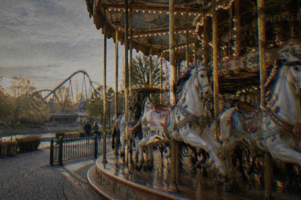 Carousel with painted horses lit in the late afternoon at an amusement park