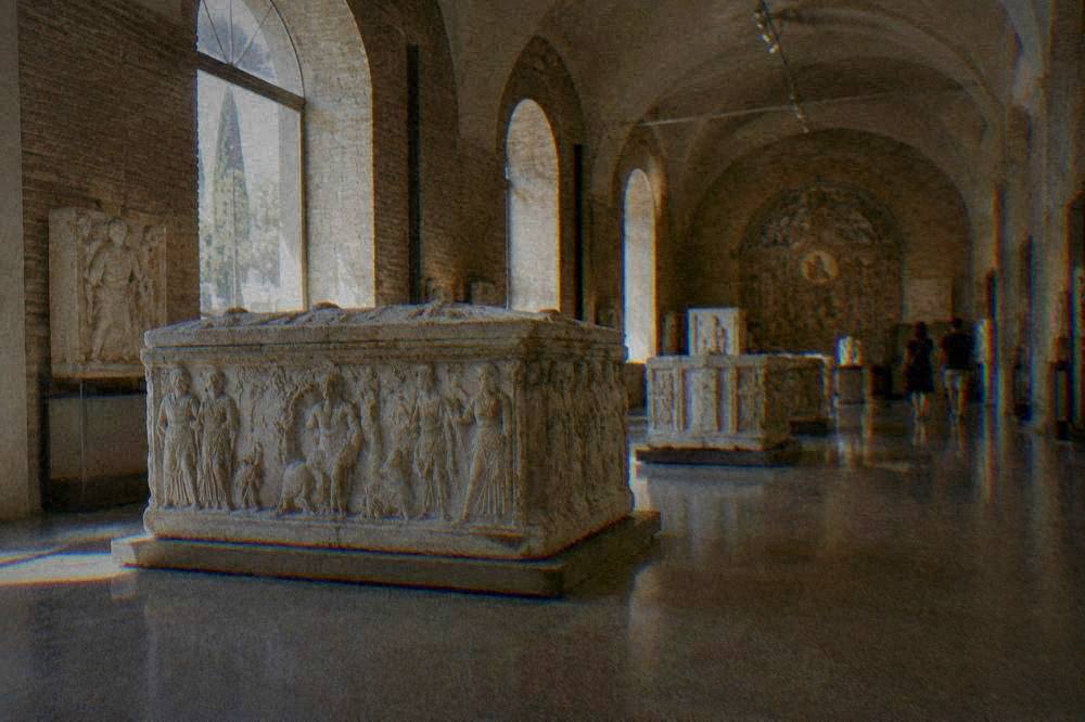 Carved stone sarcophagus displayed in a museum hall with vaulted ceiling