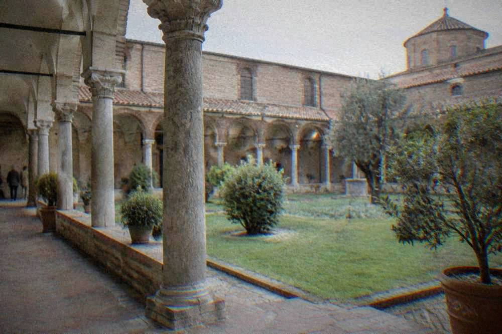 Arcaded cloister courtyard with stone columns and potted plants