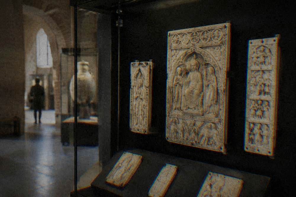 Display case of ancient carved ivory panels lit against a dark backdrop