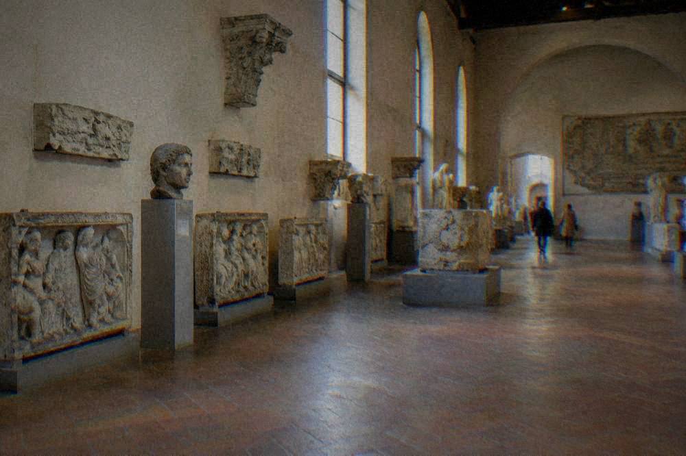 Wide view of a museum hall with sculpture fragments along the walls