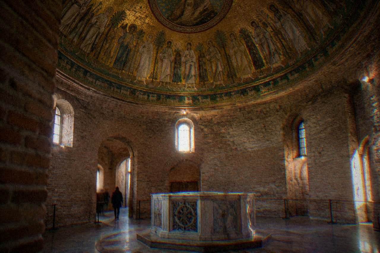Interior of a small brick baptistery with a domed ceiling covered in gold mosaic figures