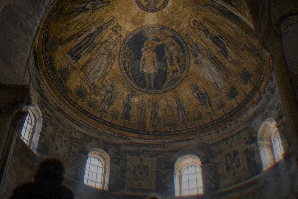 Close view of a mosaic dome with golden sky, apostle figures and a central baptism scene