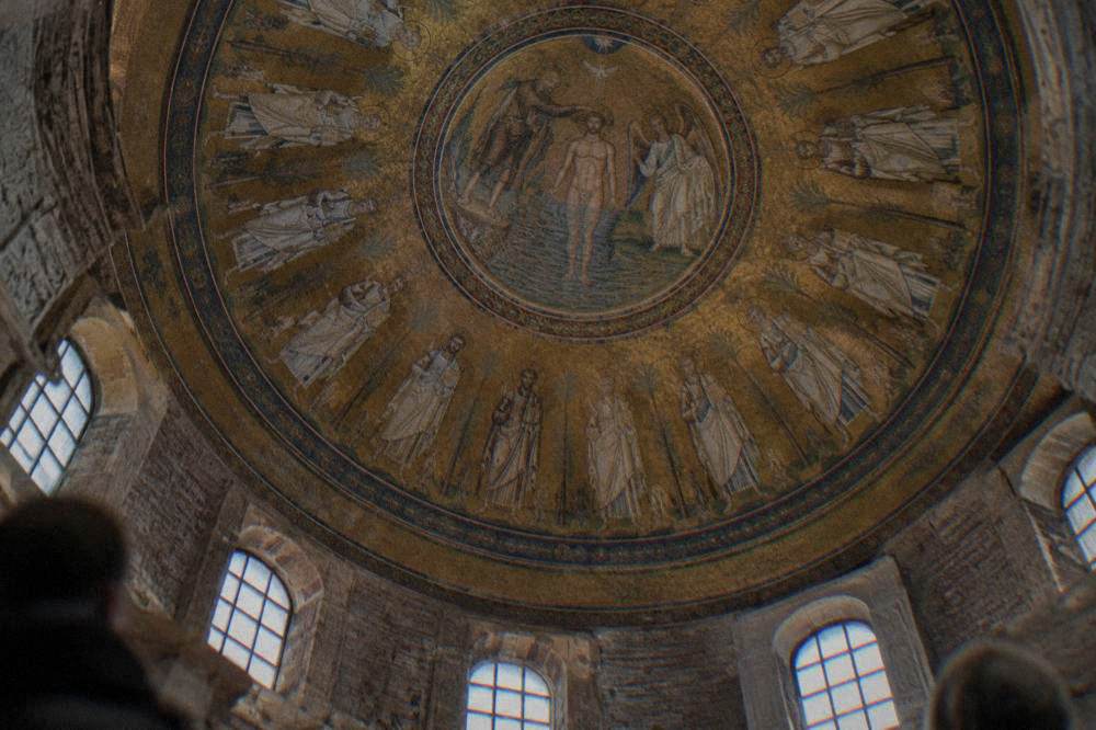 Gold mosaic medallion of a baptism scene ringed by apostle figures inside a dome