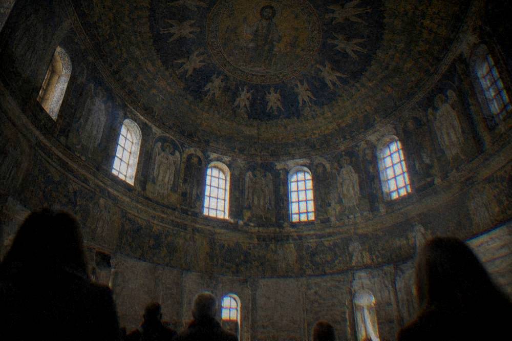 Visitors standing in a small domed room looking up at a mosaic ceiling
