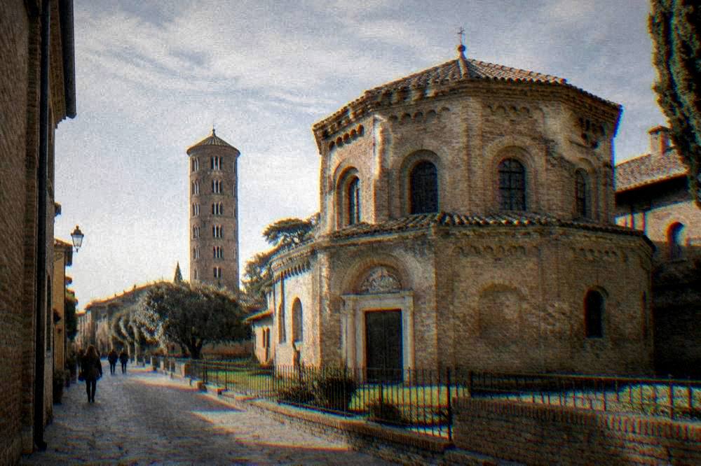Sunlit Italian street with old brick buildings and a church tower in the background