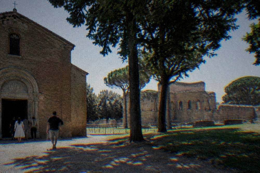 A guide speaking to a small group outside a brick church in Ravenna