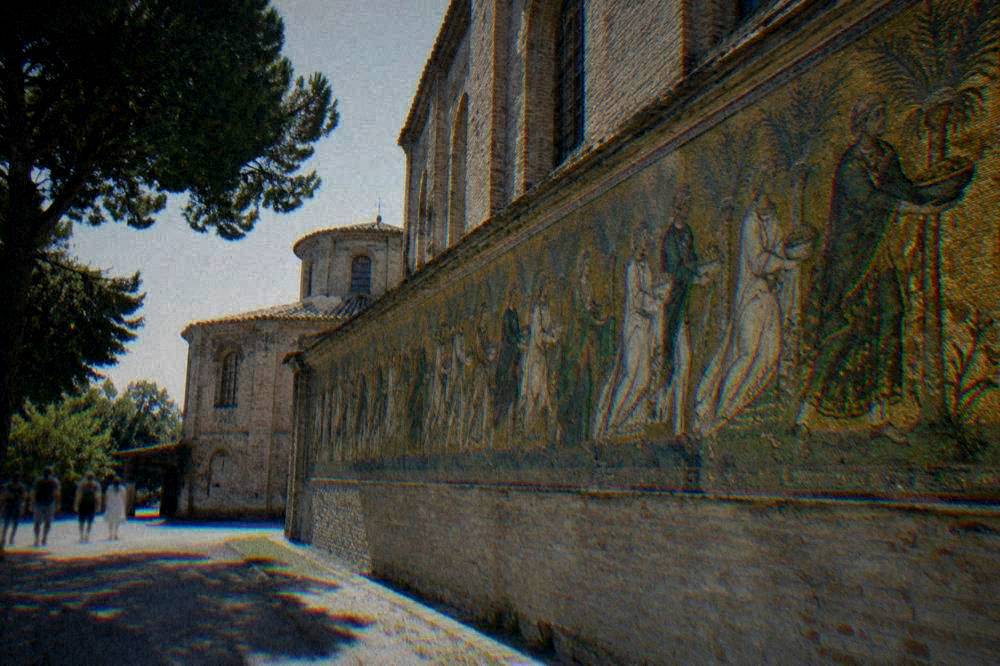 A procession of mosaic figures in gold and green along the wall of an early basilica