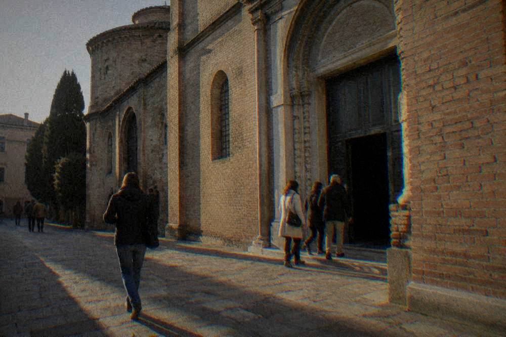 A guide speaking to a small group outside a brick church in an Italian street