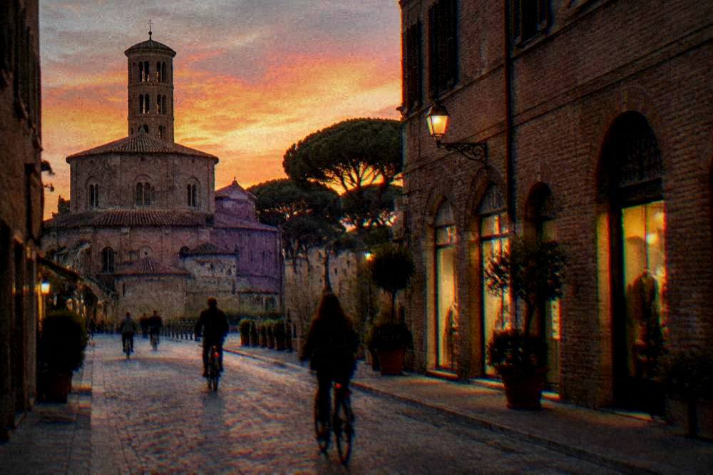 An evening street in Ravenna with lit shopfronts and cyclists passing old brick buildings