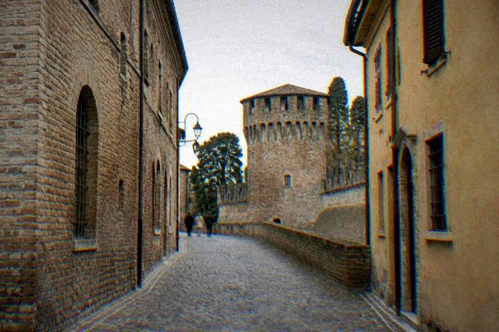 A narrow cobbled street in Ravenna lined with old brick and ochre buildings
