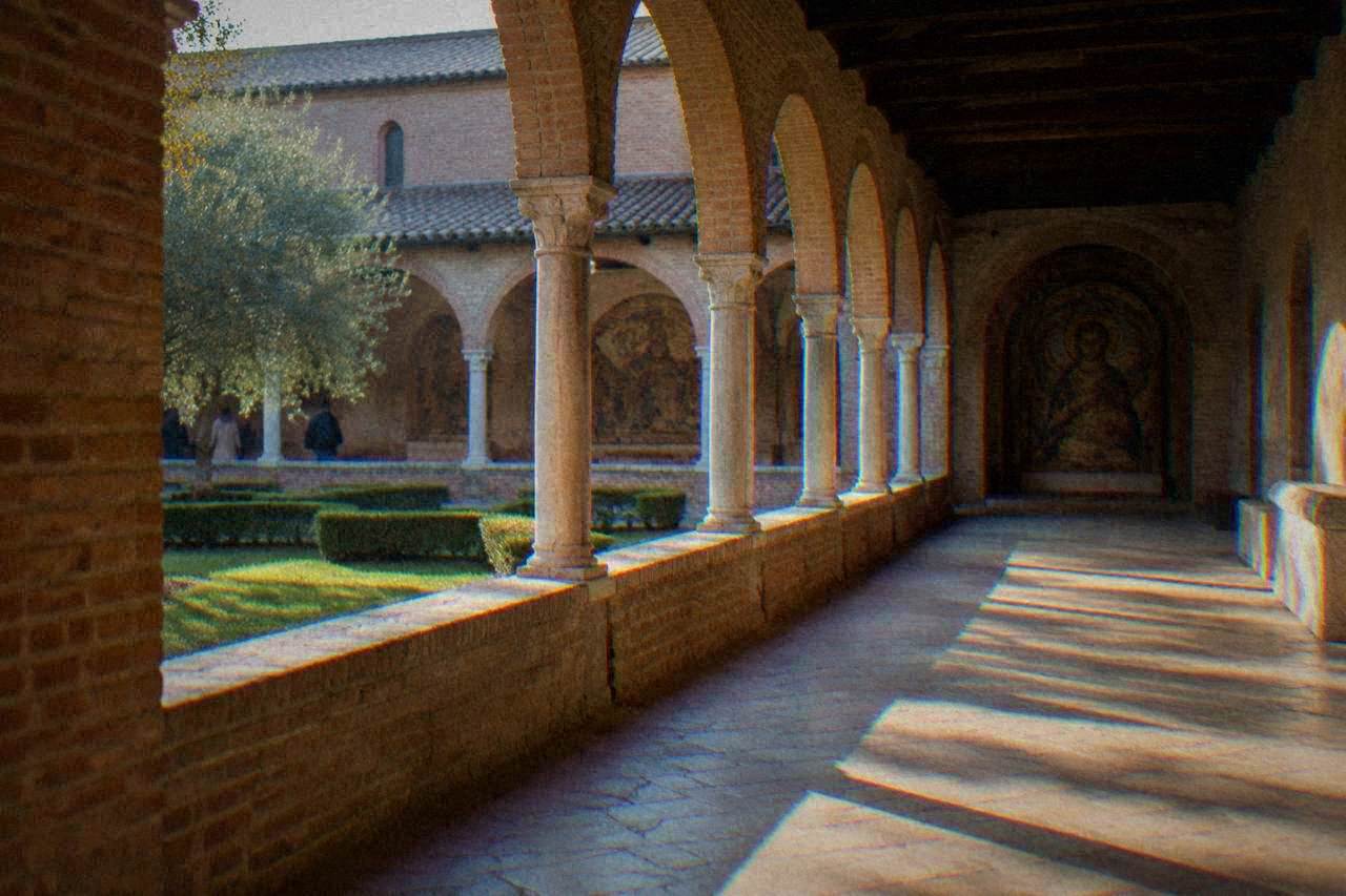A former monastery cloister in Ravenna with brick arches and a quiet stone walkway