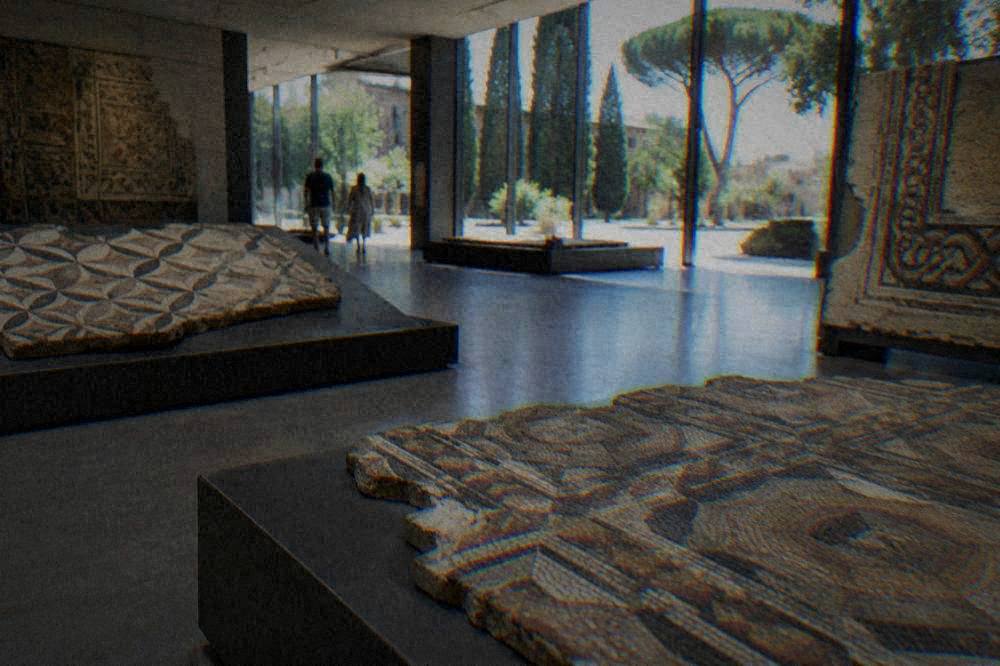 A display of ancient Roman mosaic floor fragments with geometric patterns in a museum gallery