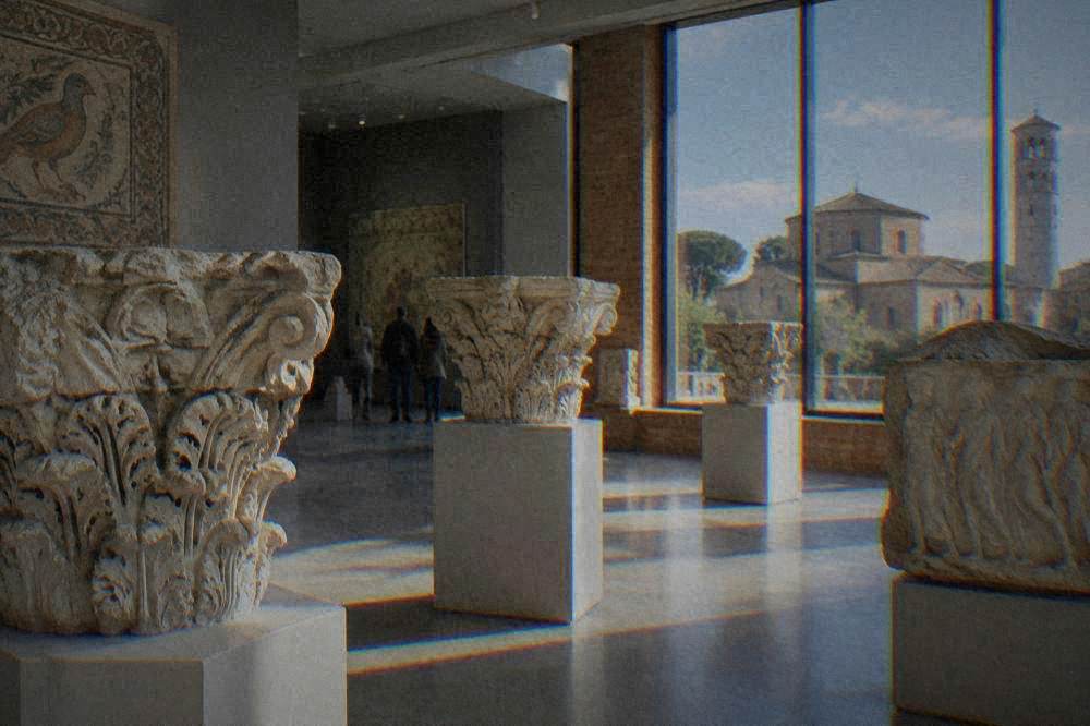 A museum gallery with stone capitals and ancient carved marbles arranged on plinths
