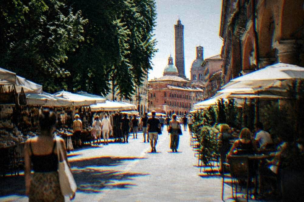 Shoppers and cafés on a busy market street in Bologna