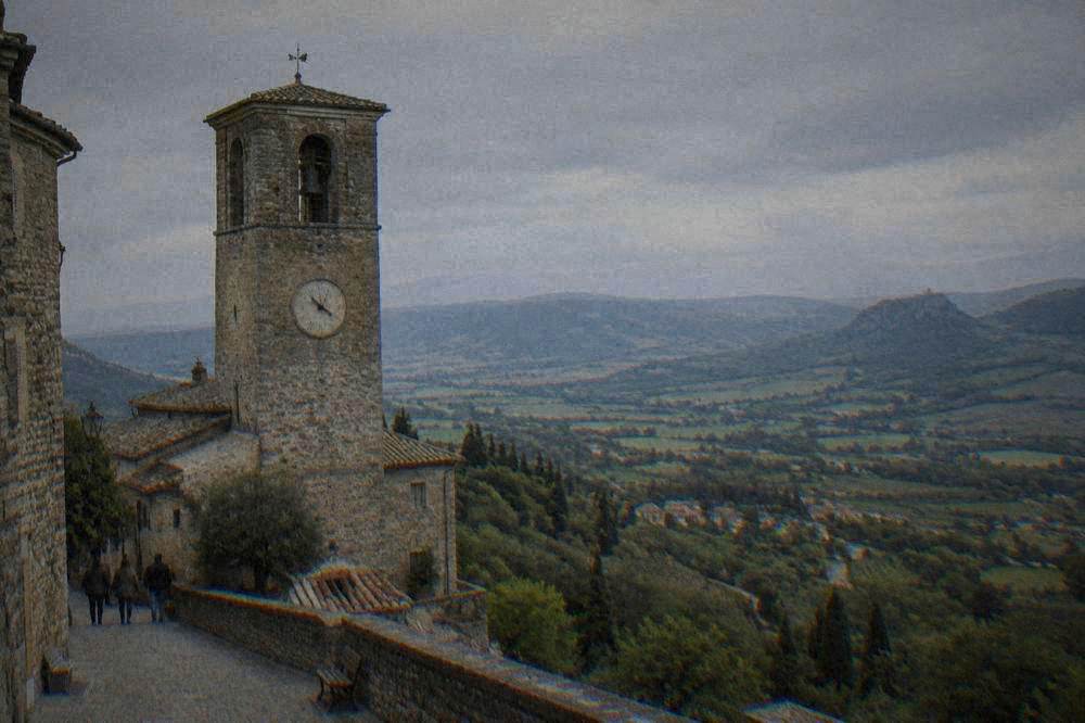 A stone fortress with crenellated walls standing on a rocky crag above a small town