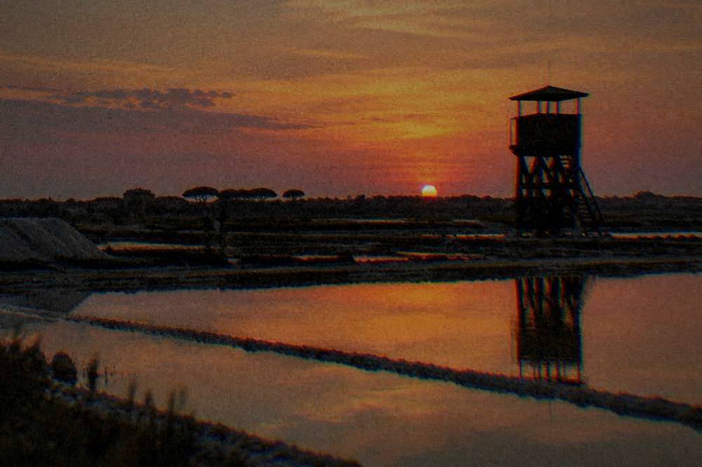 Evening light over shallow salt-pan pools at Cervia with a wooden watchtower silhouette