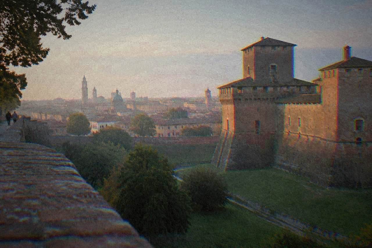 A walled Renaissance city skyline with a brick castle rising above rooftops on a flat plain