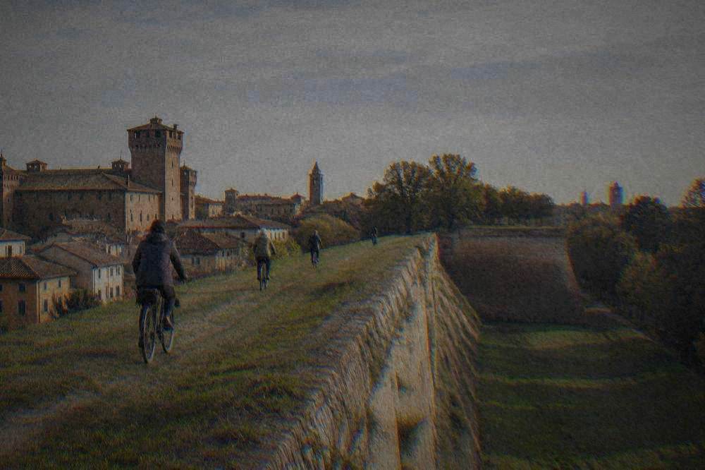 Cyclists riding along a grassy path on top of a broad old city wall
