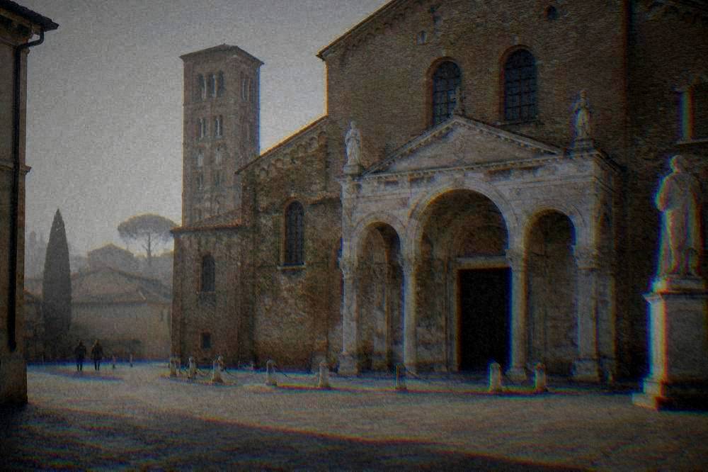A brick cathedral facade with a marble porch and statues on a quiet square