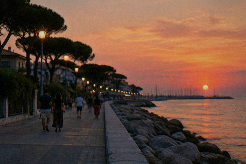 An evening promenade beside the sea with lamps lit and people strolling