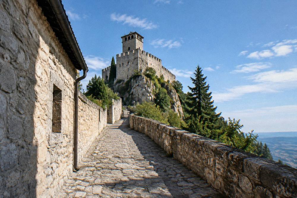 A narrow stone street in San Marino lined with shops and leading toward a stone tower