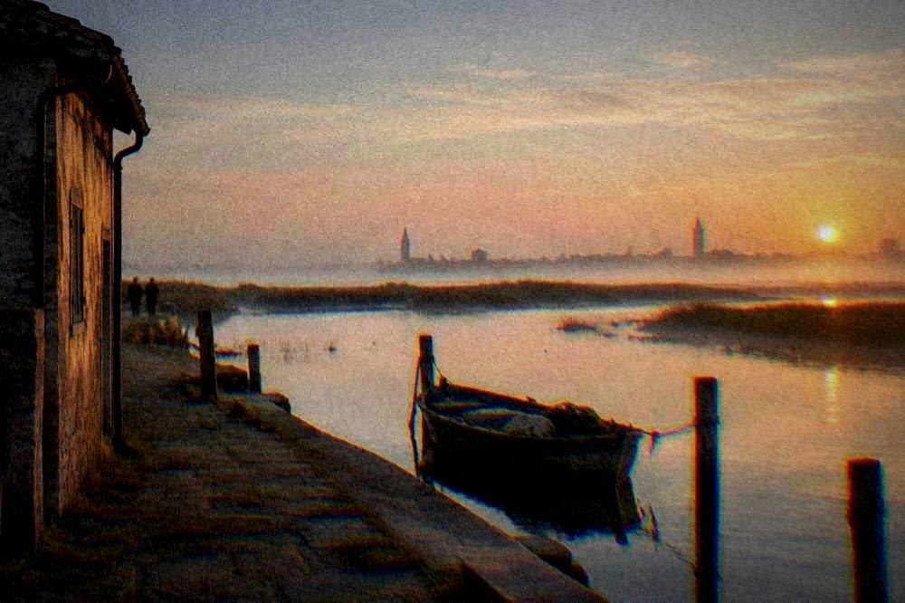 A canal in Comacchio with a brick footbridge and moored small boats