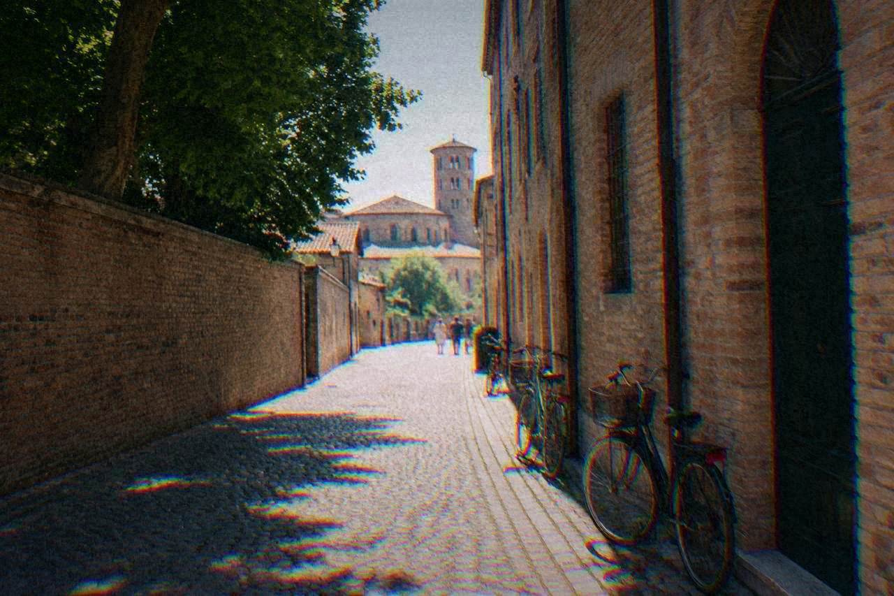 A quiet cobbled street in Ravenna historic centre with old brick buildings and bicycles parked against a wall