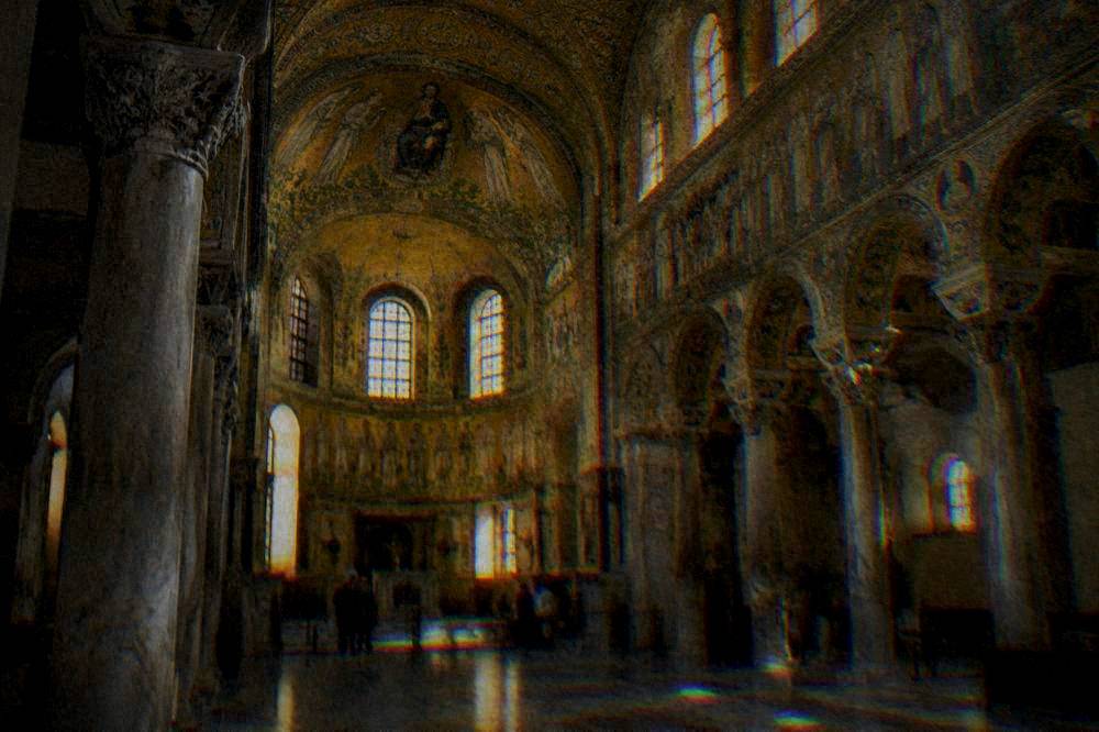 The interior of a Ravenna church with gold mosaic vaults lit softly