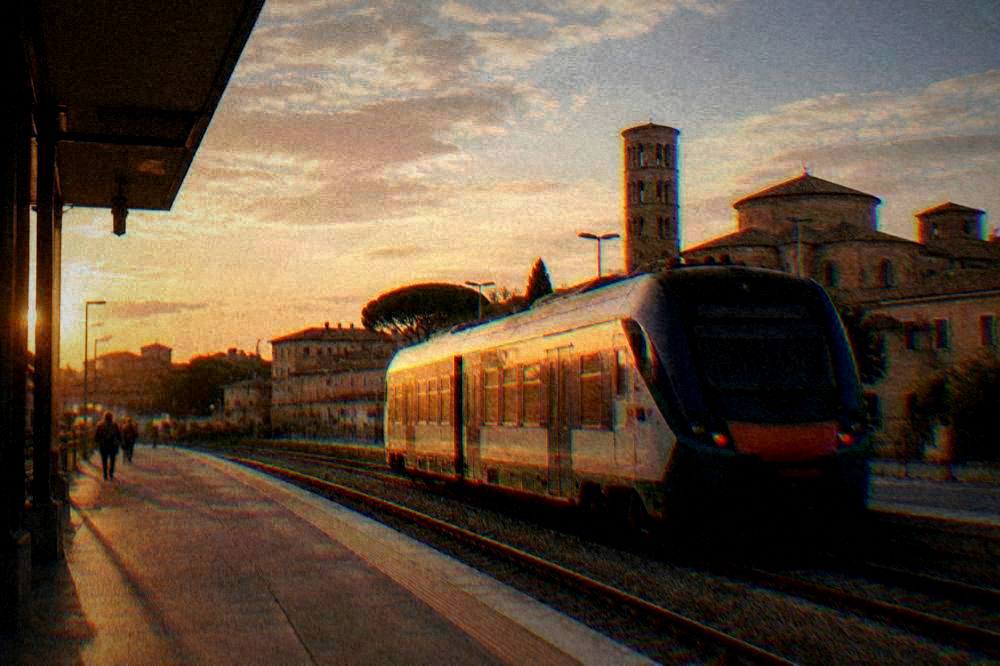 A regional train waiting at Ravenna station platform under a wide sky