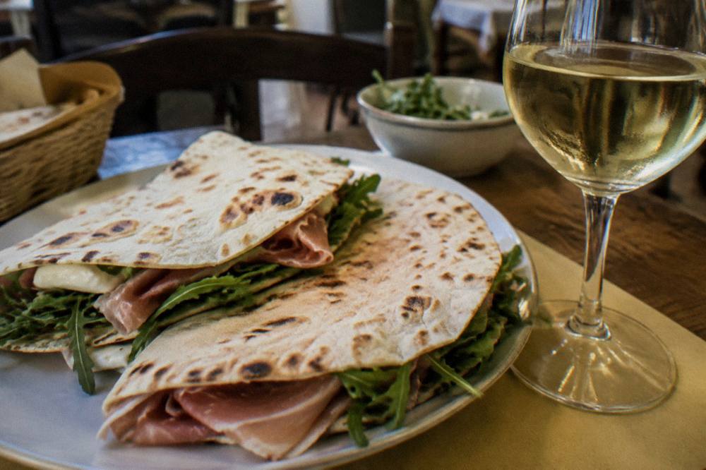A table set with piadina bread and a glass of white wine in a small Ravenna trattoria