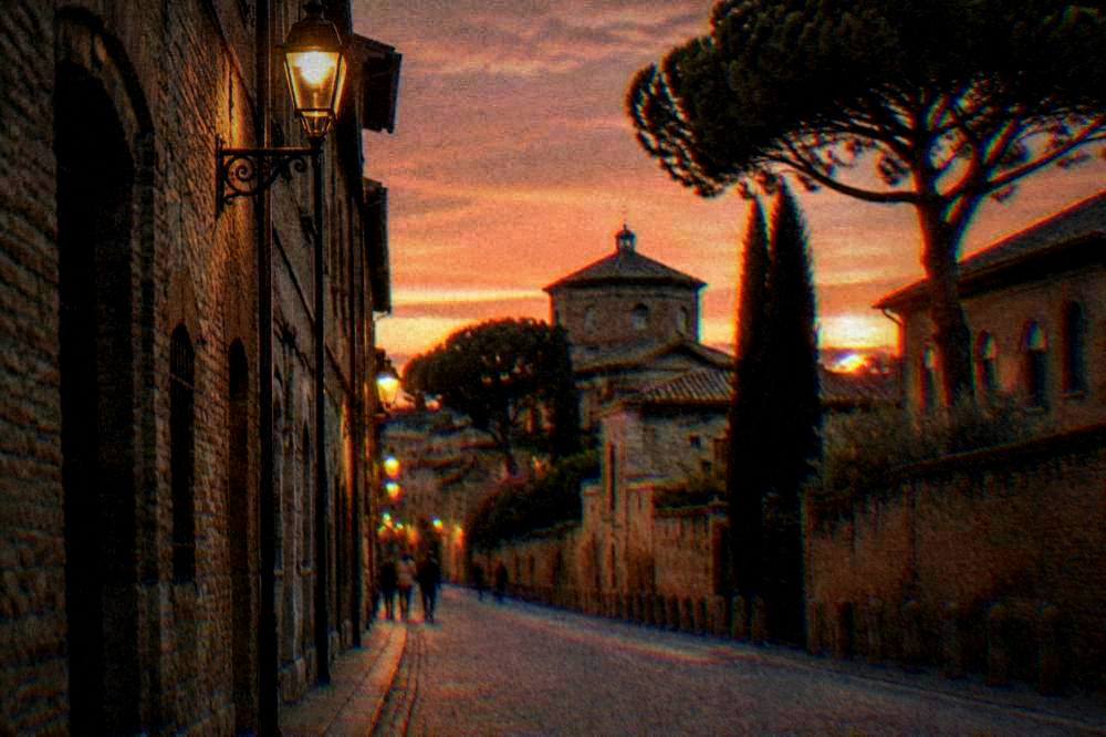 An evening view of a Ravenna street with warm lamplight on brick facades
