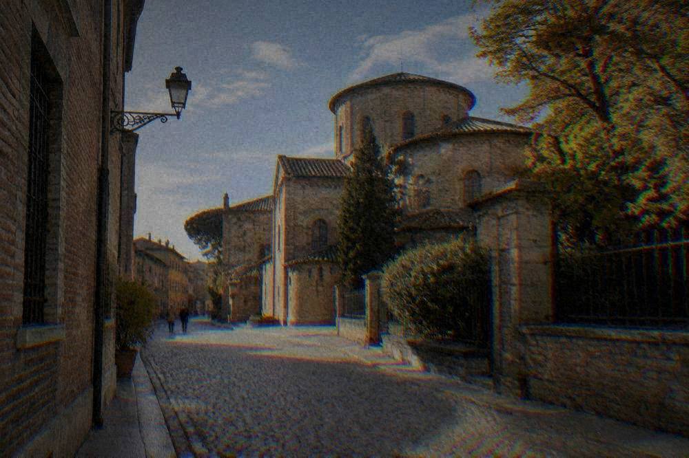 A quiet cobbled street in Ravenna historic centre under a soft autumn sky