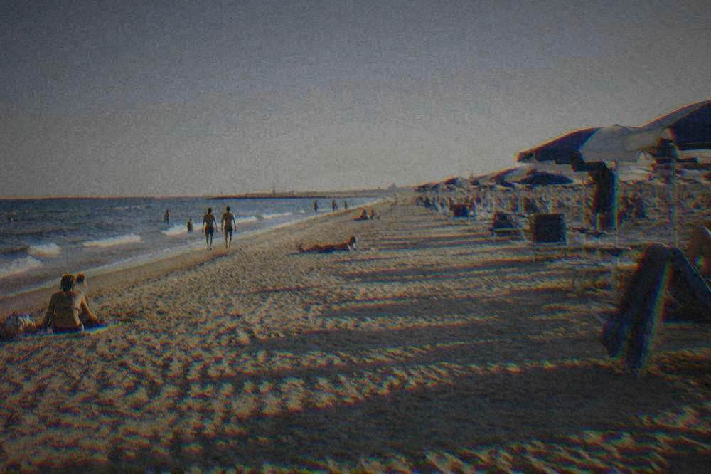 Sunbathers on a wide sandy Adriatic beach beside rows of sun umbrellas near Ravenna