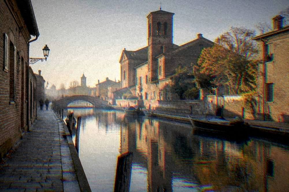 Canal and brick buildings in Comacchio with autumn light on the water