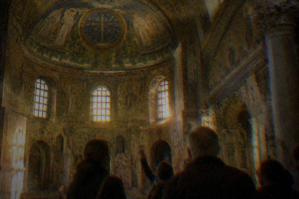 A small group with a guide looking up at mosaics in a Ravenna baptistery