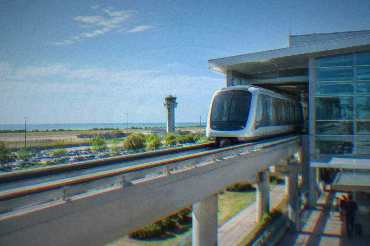 A travellers monorail car leaving an airport terminal building in daylight