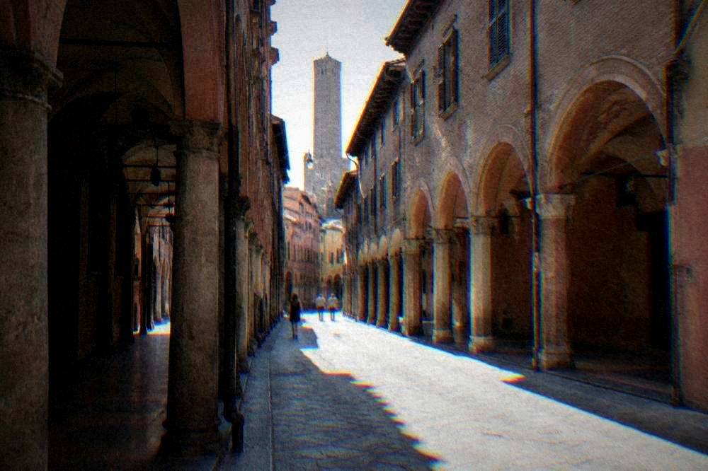 A porticoed medieval street in Bologna with brick buildings on both sides