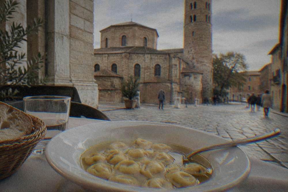 A bowl of steaming cappelletti in clear golden broth with a spoon