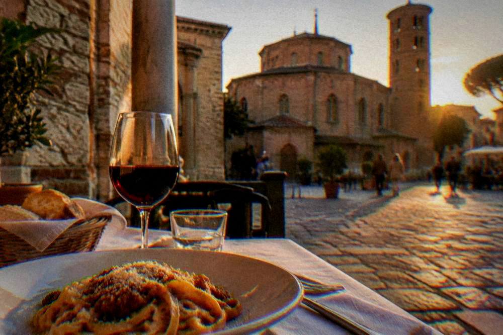 A restaurant table in Ravenna with pasta, bread and a glass of red wine