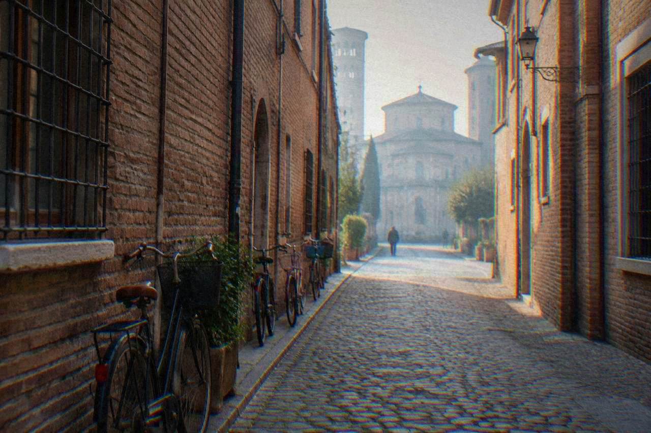 A quiet cobbled street in the centre of Ravenna with parked bicycles and old brick facades