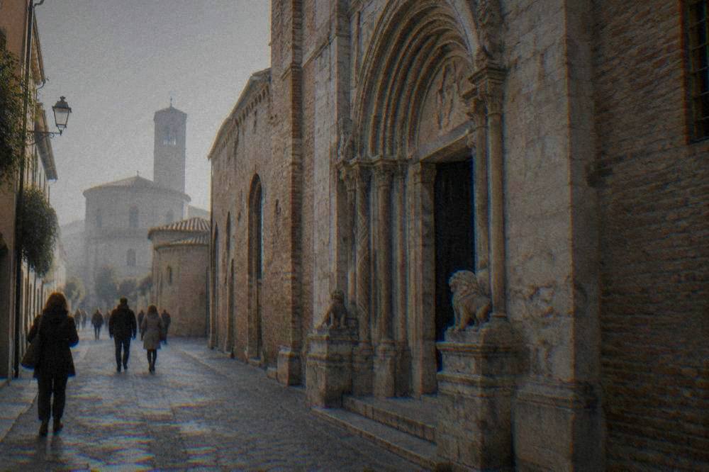 Pedestrians walking past a stone church facade in Ravenna's narrow historic streets