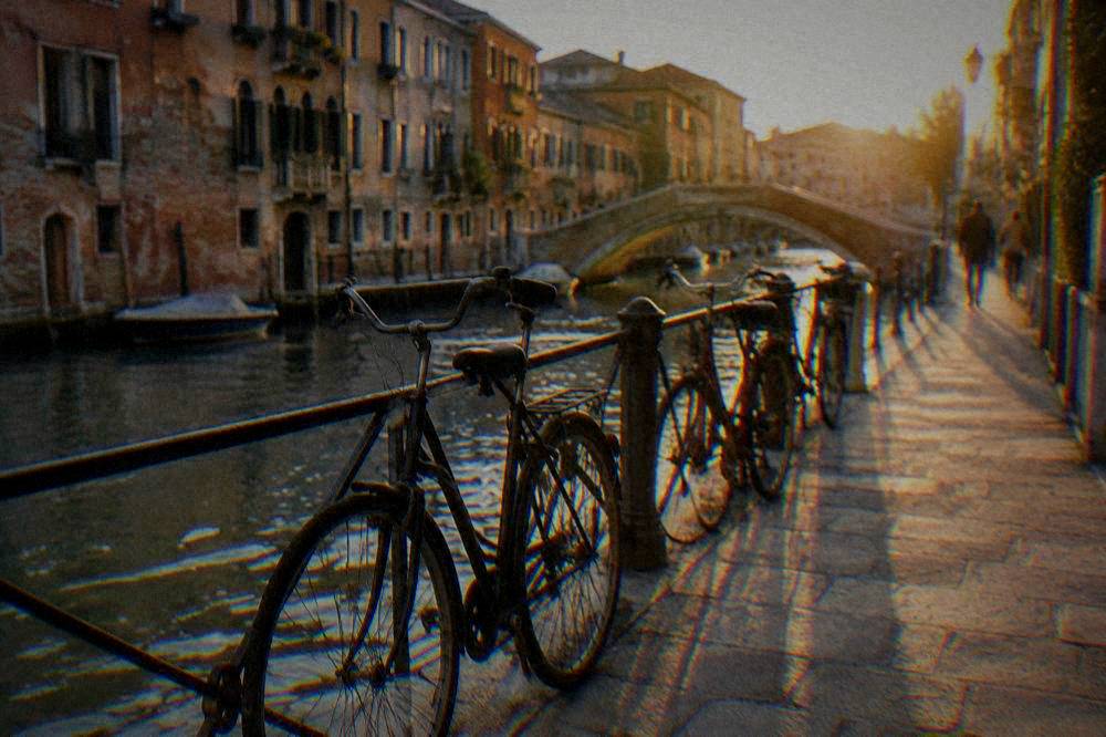 Bicycles leaning against a railing beside a canal path near Ravenna