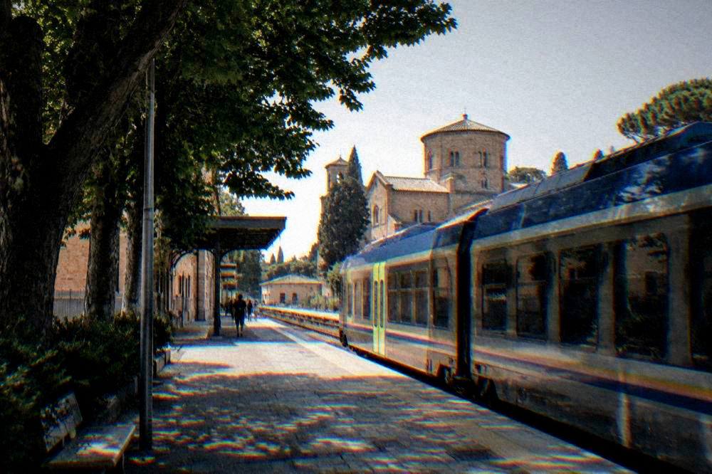 A regional train waiting at a platform in a small Italian railway station
