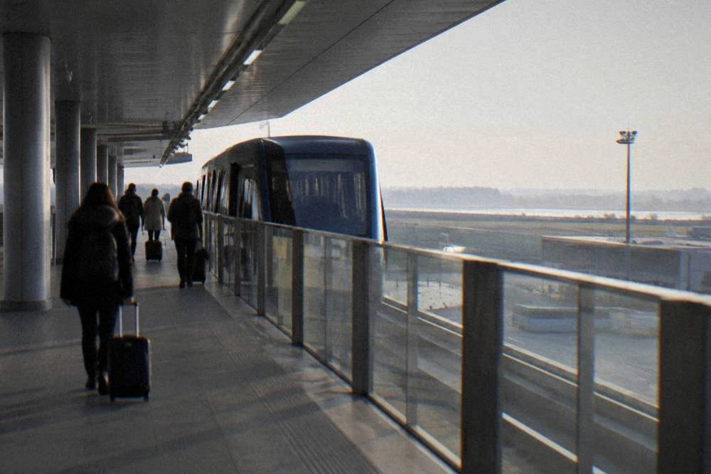 An overhead people mover station at an Italian airport with travellers on the platform