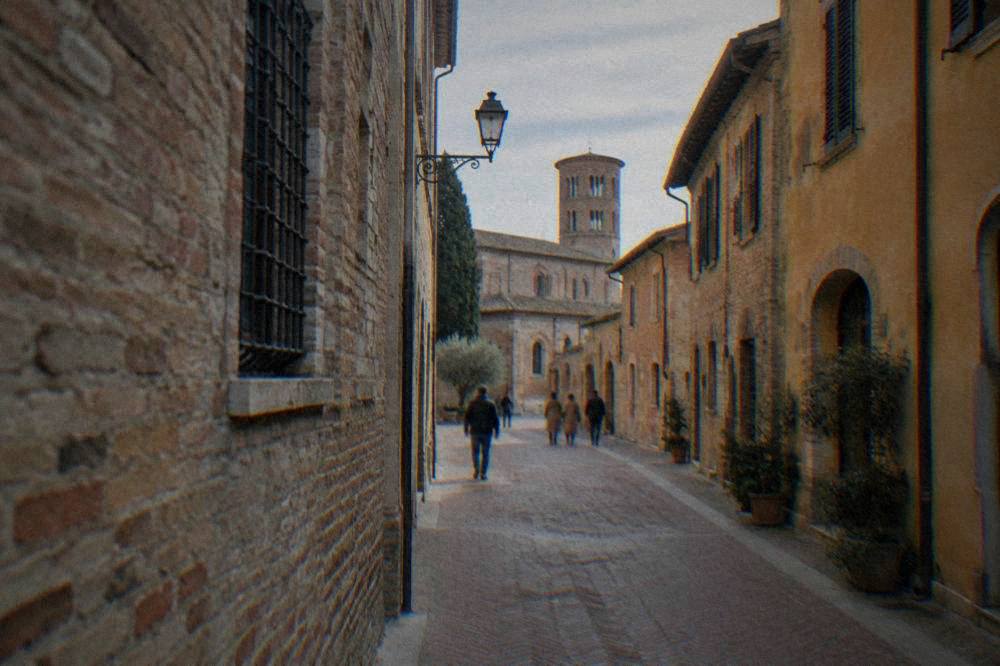 People walking down a narrow brick-paved street in an Italian old town