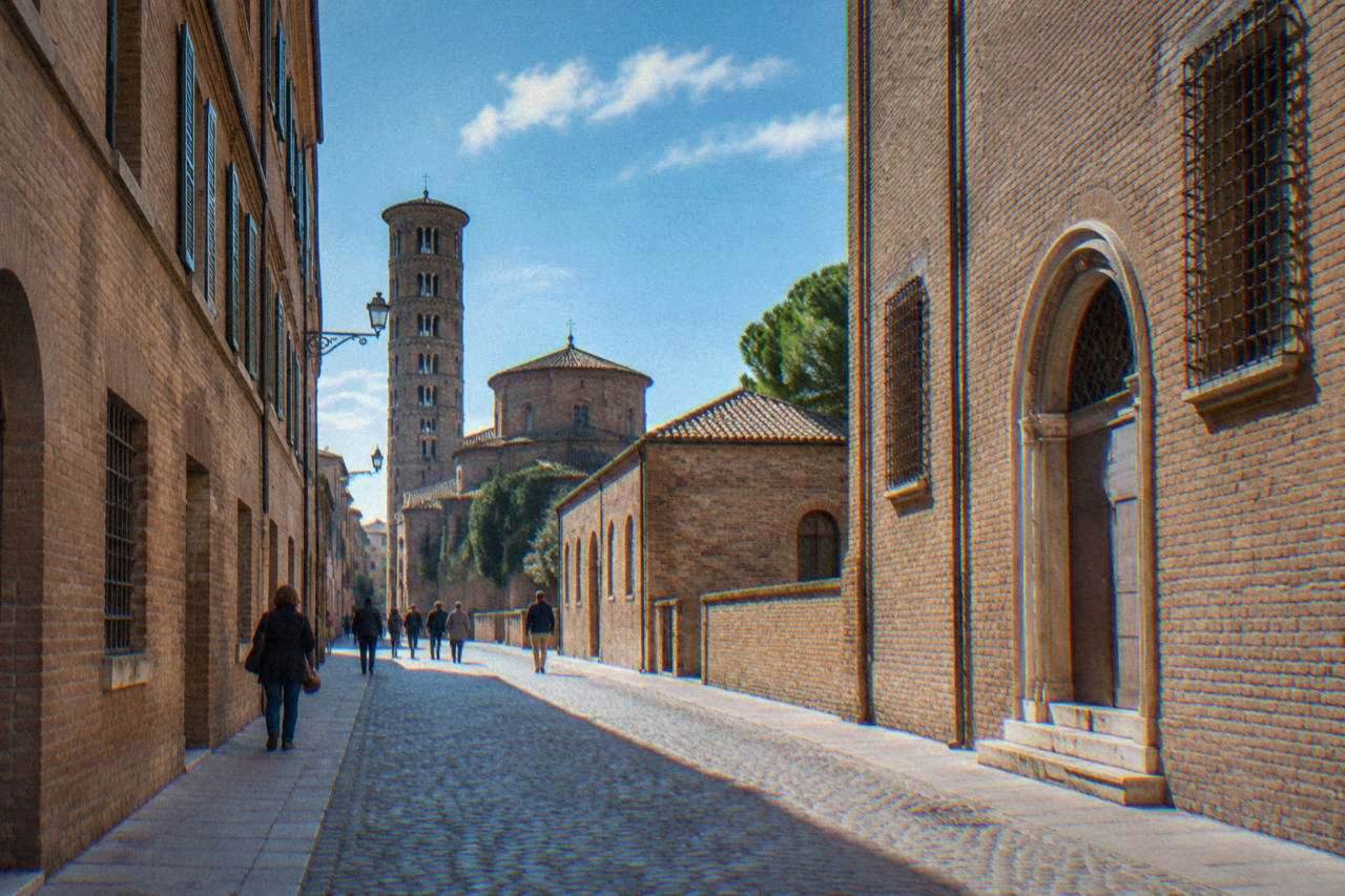 A quiet cobbled street in Ravenna lined with brick buildings and a few pedestrians in daylight