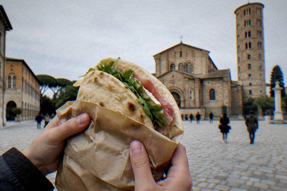 A table with a warm flatbread, a knife and a small glass of red wine
